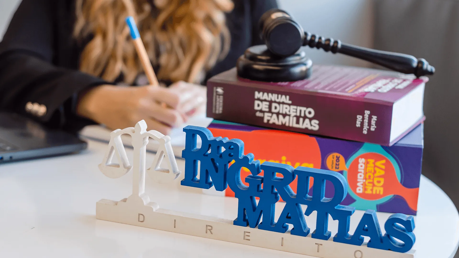 Mesa do escritório com placa Dra. Ingrid Matias, martelo e livros de Direito de Família